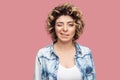 Portrait of funny young beautiful woman with makeup and curly hairstyle in casual blue shirt standing, winking and looking at Royalty Free Stock Photo