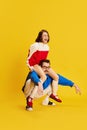 Portrait with funny, young couple, woman sitting on husband& x27;s back over blue studio background. Bossy wife Royalty Free Stock Photo