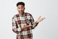 Portrait of funny young dark-skinned beautiful man with afro hairstyle in casual shirt smiling, showing white background Royalty Free Stock Photo