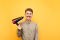 Portrait of funny young man in glasses and shirt on yellow background looking into camera with crazy face. Expressive fun guy uses Royalty Free Stock Photo