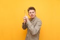 Portrait of a funny young man standing on a yellow background and using a banana as a weapon,looking camera with a serious face Royalty Free Stock Photo