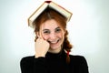 Portrait of funny young smiling student girl with an open book on her head. Reading and education concept Royalty Free Stock Photo