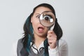 Portrait of a funny young woman looking at the camera through magnifying glass on gray background Royalty Free Stock Photo