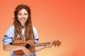 Portrait of funny young woman playing ukulele. Happiness and carefree concept