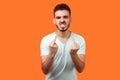 Portrait of furious aggressive brunette man showing middle fingers, fuck off expression. indoor studio shot isolated on orange