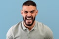 Portrait of furious arab man shouting with rage at camera, screaming with fury, standing over blue background Royalty Free Stock Photo