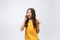 Portrait of a furious asian woman talking on mobile phone over white background