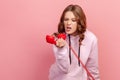 Portrait of furious young curly haired female screaming while talking phone, displeased with information