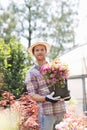 Portrait of gardener holding flower pot outside greenhouse