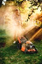 Portrait of gardener mowing the lawn using a gasoline powered device, a professional lawn mower