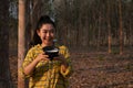Portrait gardener young asea woman hand holding a full cup of raw para rubber milk of tree in plantation rubber tapping form