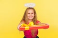 Portrait of generous delighted child girl with long blond hair and angelic halo holding gift box and smiling to camera