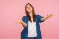 Portrait of generous kind-hearted girl in checkered shirt raising arms in gesture take everything for free