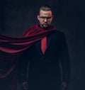 Portrait of a genius superhero in a black suit with a red tie on a dark background. Royalty Free Stock Photo