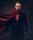 Portrait of a genius superhero in a black suit with a red tie on a dark background. Royalty Free Stock Photo