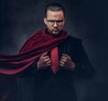 Portrait of a genius superhero in a black suit with a red tie on a dark background. Royalty Free Stock Photo