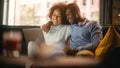 Portrait of Gentle Black Couple Using Laptop Computer, While Sitting on a Couch in Cozy Stylish