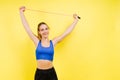 Portrait of gentle muscular woman holding skipping rope on her neck isolated over yellow background Royalty Free Stock Photo