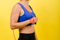 Portrait of gentle muscular woman holding skipping rope on her neck isolated over yellow background Royalty Free Stock Photo