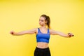 Portrait of gentle muscular woman holding skipping rope on her neck isolated over yellow background Royalty Free Stock Photo