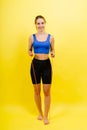 Portrait of gentle muscular woman holding skipping rope on her neck isolated over yellow background Royalty Free Stock Photo