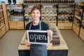 Portrait of girl assistant wearing apron welcoming inviting open