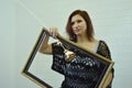 Portrait of a girl with a wooden rose and a frame for a picture on a white background. A young woman holds a wooden baguette for a Royalty Free Stock Photo