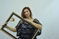 Portrait of a girl with a baguette for a picture on a white background. A young woman with a wooden rose and a frame looks at the Royalty Free Stock Photo