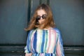 Portrait of a girl in a beautiful summer dress and sunglasses stands near an old wooden green door on a sunny day. Summer trip to Royalty Free Stock Photo