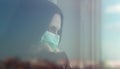 Portrait of Girl behind closed window wearing protective mask and looking out with copy space Royalty Free Stock Photo