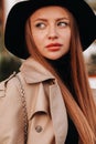 Portrait of a girl in a beige coat and black hat on a city street. Women`s street fashion. Autumn clothing.Urban style Royalty Free Stock Photo
