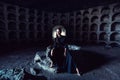 Portrait of a girl in a black dress with a white collar sitting on a stone well in a stone opening. Royalty Free Stock Photo