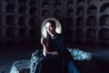 Portrait of a girl in a black dress with a white collar sitting on a stone well in a stone opening. Royalty Free Stock Photo