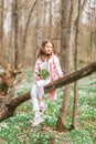 Portrait of a girl with a bouquet of anemone. A child in the spring forest