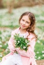 Portrait of a girl with a bouquet of anemone. A child in the spring forest