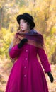 Portrait girl in a bright crimson coat in sunny autumn day outdo