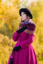 Portrait girl in a bright crimson coat in sunny autumn day outdo