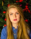 Portrait of a girl with bright red lips, blond long hair against the background of a New Year tree. Young girl in a blue men`s Royalty Free Stock Photo