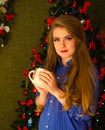 Portrait of a girl with bright red lips, blond long hair against the background of a New Year tree. Young girl in a blue men`s