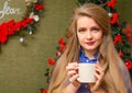 Portrait of a girl with bright red lips, blond long hair against the background of a New Year tree. Young girl in a blue men`s