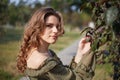 Portrait of a girl carried tree branches, on a bright day in the summer in the backlight, in a dress with bare shoulders. At