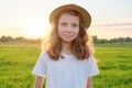 Portrait girl child 9, 10 years old in hat, summer green meadow sunset background Royalty Free Stock Photo