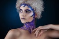 Portrait of a girl with creative make-up on a dark blue background. Purple - Gold Makeup. Royalty Free Stock Photo