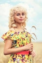 Portrait of a girl with curly blond hair, holding ripe spikelets of barley in her hands