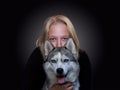 Portrait of a girl and a dog with blue eyes on a dark background Royalty Free Stock Photo