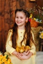 Portrait of a girl in a dress with a newborn yellow chick in a studio with a wooden background and hay. A pretty child laughs Royalty Free Stock Photo