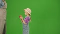 Portrait of girl in dress and rubber boots on chroma key green screen. Small cute girl gardener holding ripe red apple