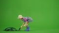 Portrait of girl in dress and rubber boots on chroma key green screen. Small cute girl gardener planting seeds in soil