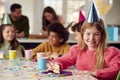 Portrait Of Girl Eating Birthday Cake At Party With Parents And Friends At Home Royalty Free Stock Photo