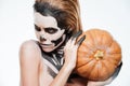 Portrait of girl with fearful halloween makeup holding pumpkin